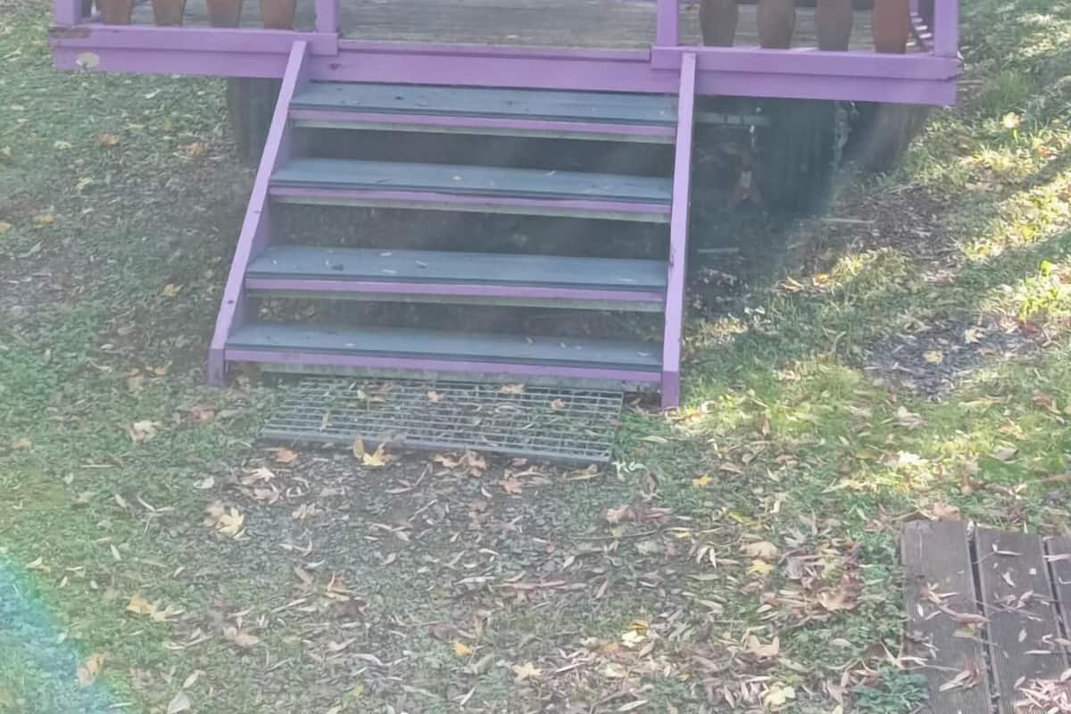 Une petite cabane en bois avec une porte violette et un balcon.