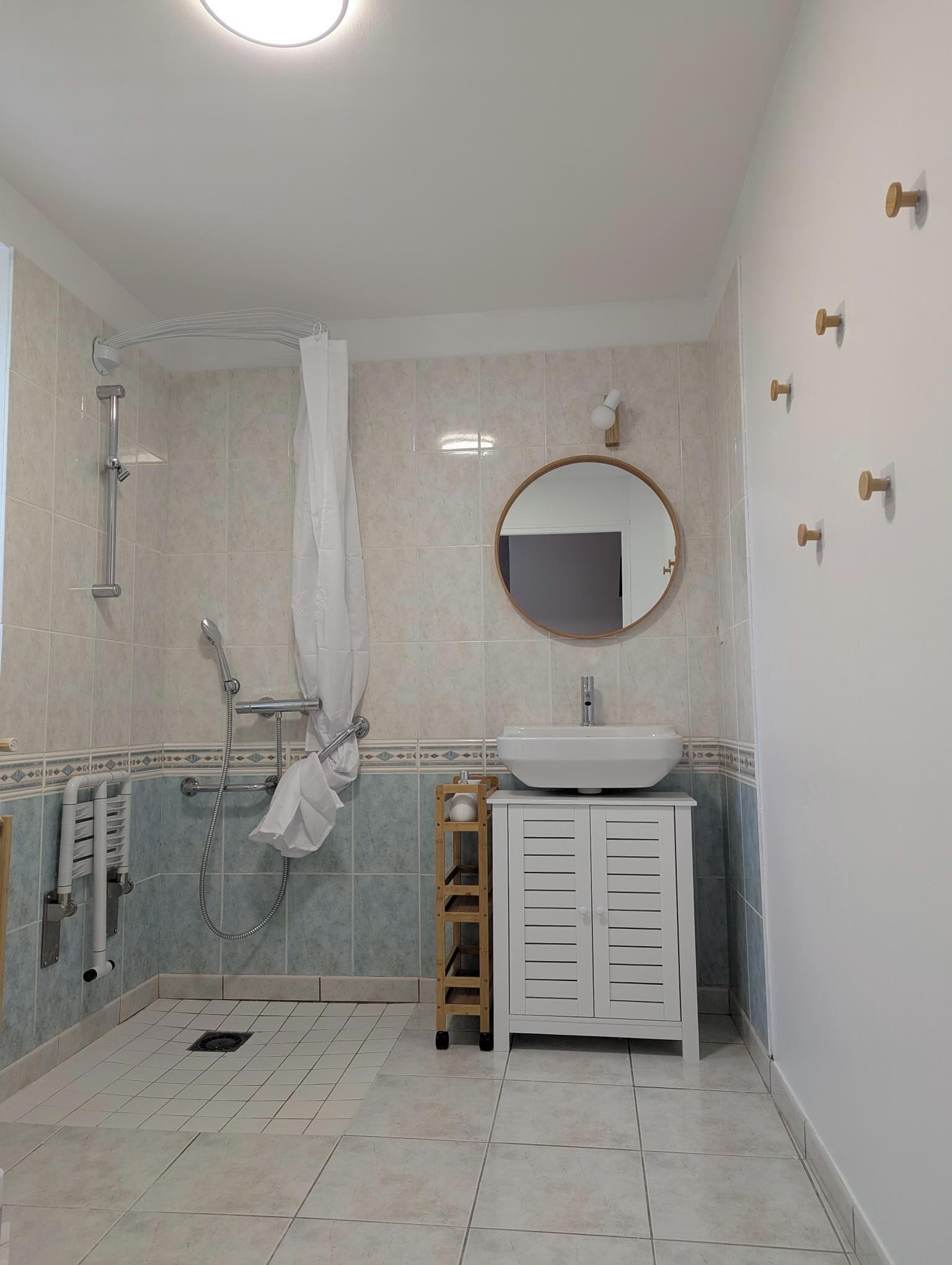 A bathroom with a shower, a sink, a mirror, and a towel rack.