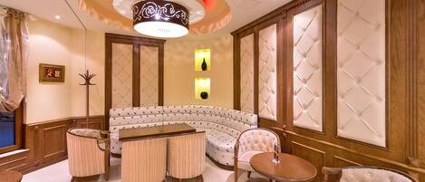 A luxurious room with a curved sofa, a round table, and a tufted chair.
