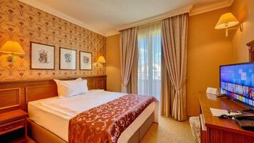 A hotel room with a large bed, a desk with a computer, and a TV.