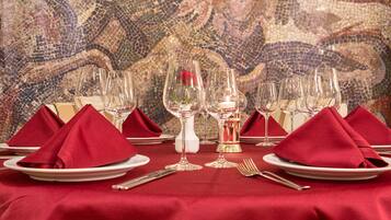 A table set for a meal with red napkins, clear glassware, and a mosaic wall in the background.