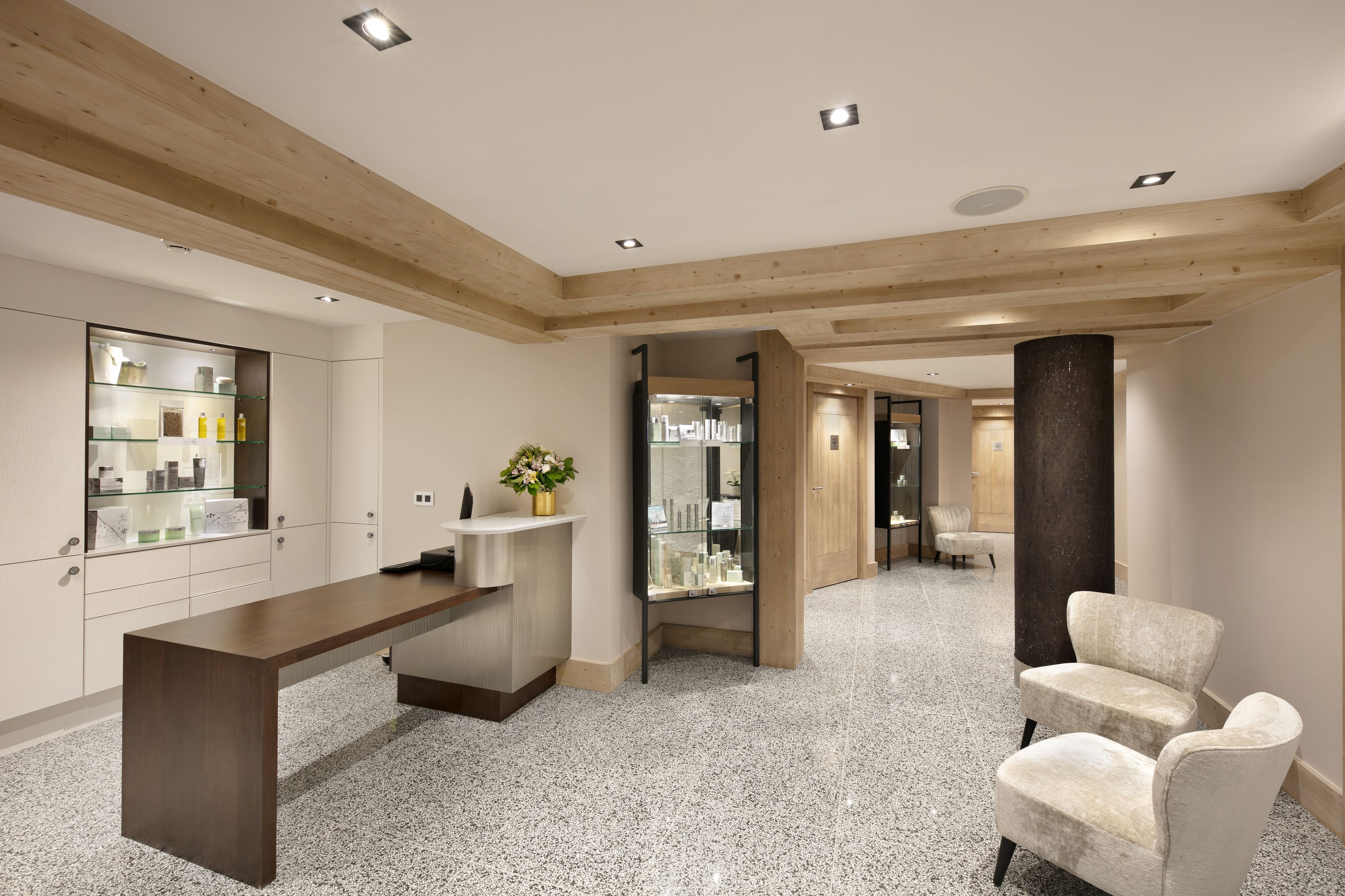 Un moderno hall de hotel con techo de madera, un mostrador de recepción, un área de descanso y una vitrina de vidrio.