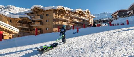 A ski resort with wooden buildings, a ski lift, and a snowy slope.