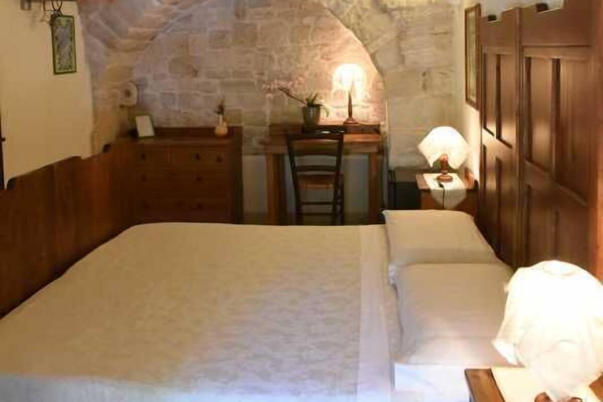 A bedroom with a stone ceiling, a bed, a desk, and a television.