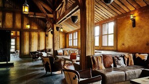 A rustic interior with wooden beams, leather furniture, and hanging lanterns. - La Cite suspendue (Plailly)