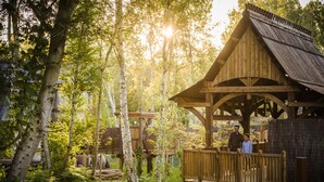 A wooden structure with a sloped roof, surrounded by trees and greenery. - La Cite suspendue (Plailly)