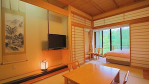 Una habitación japonesa tradicional con suelo de tatami, televisor, cama y puerta corrediza que da a un balcón.