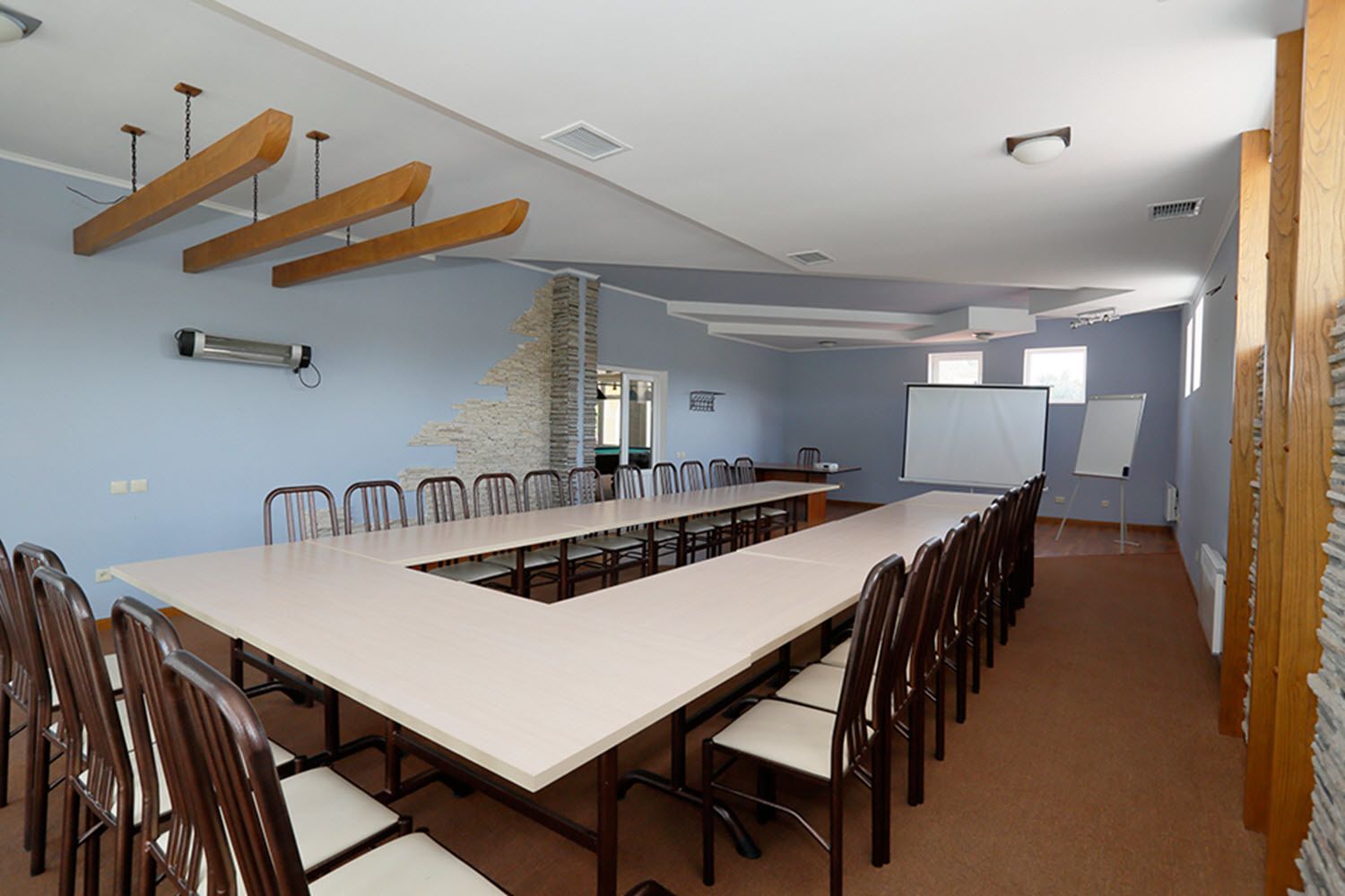 Una sala de conferencias con una larga mesa, sillas, una pizarra y una pantalla de proyector.