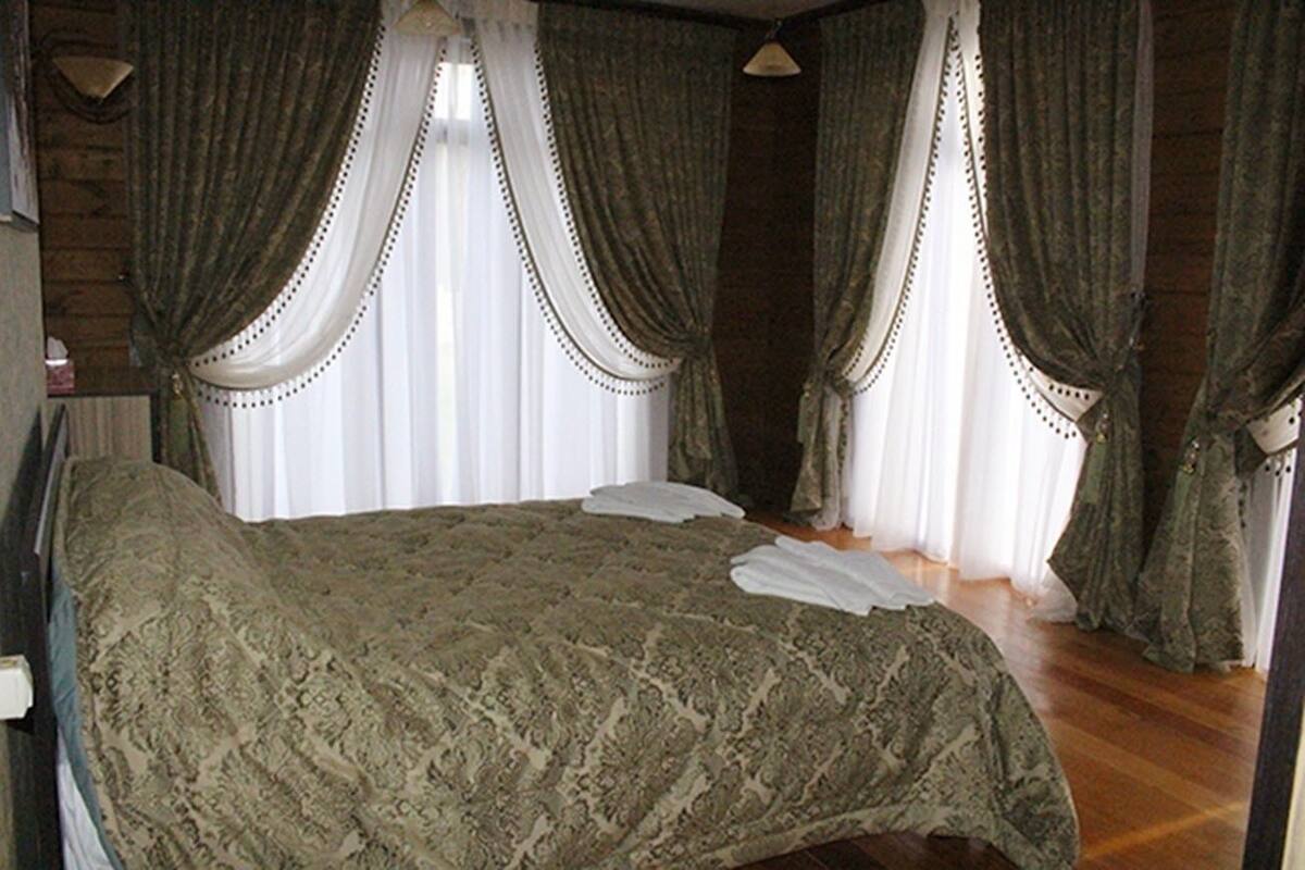 A room with a large bed, wooden walls, and curtains.