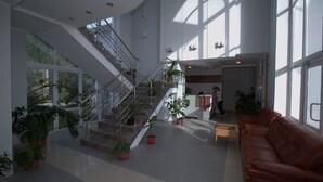 Un vestíbulo amplio con escaleras, plantas en macetas y un sofá de cuero.