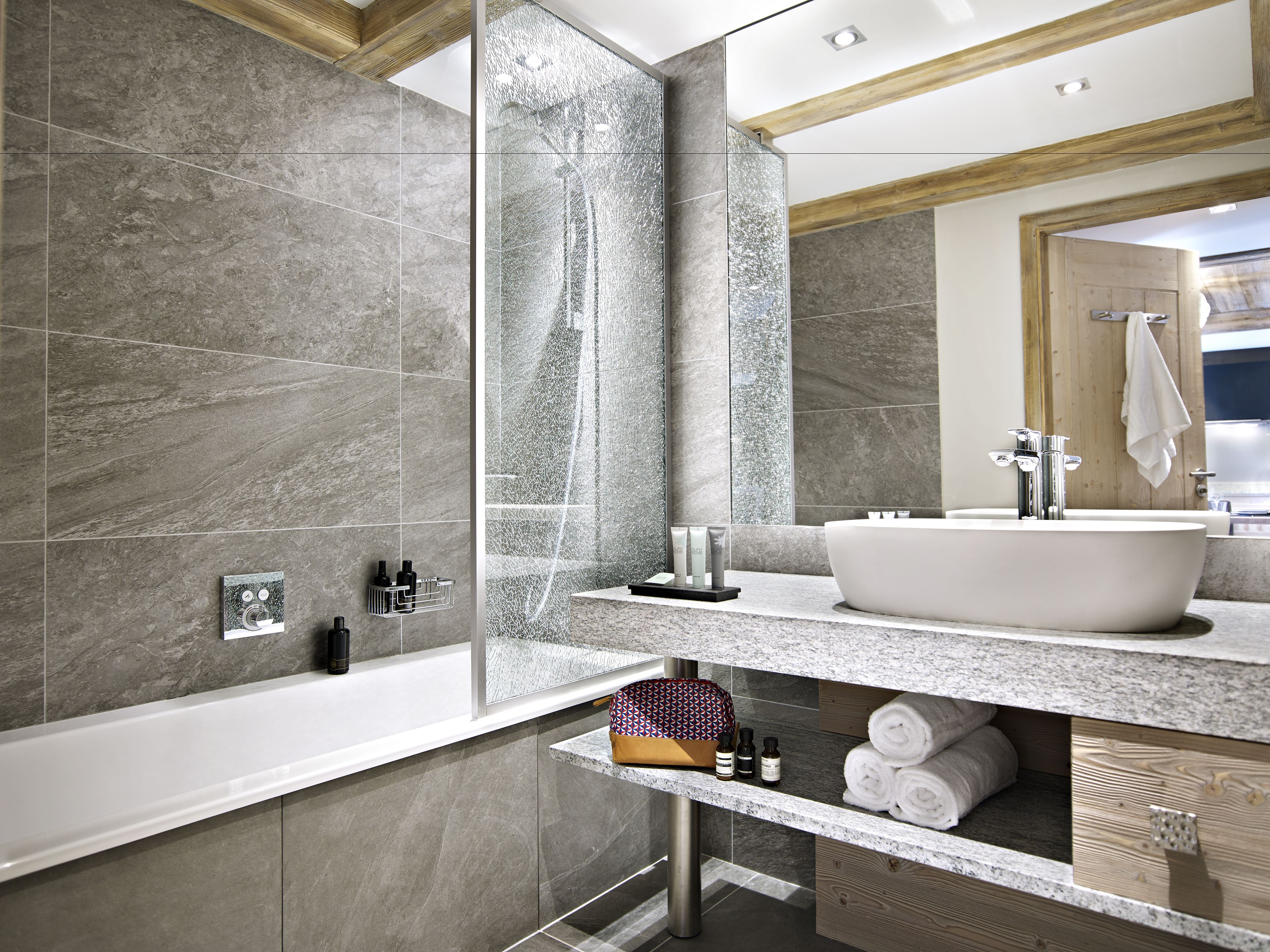 Un baño moderno con una bañera independiente, un espejo grande y un lavamanos.