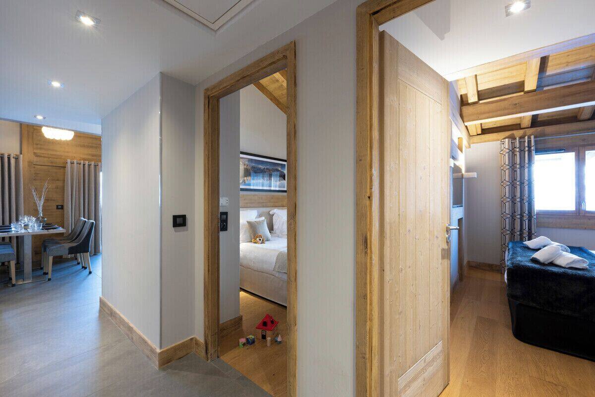 Una habitación de hotel moderna con techo de madera, una cama acogedora, un comedor con mesa y sillas, y un pequeño espacio de juegos con juguetes.