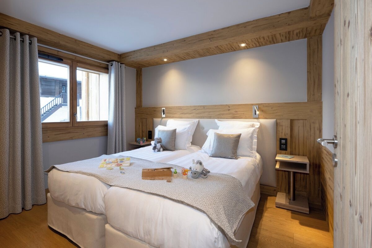 Una cama doble con cabecera de madera, una mesita de noche y una ventana con cortinas.