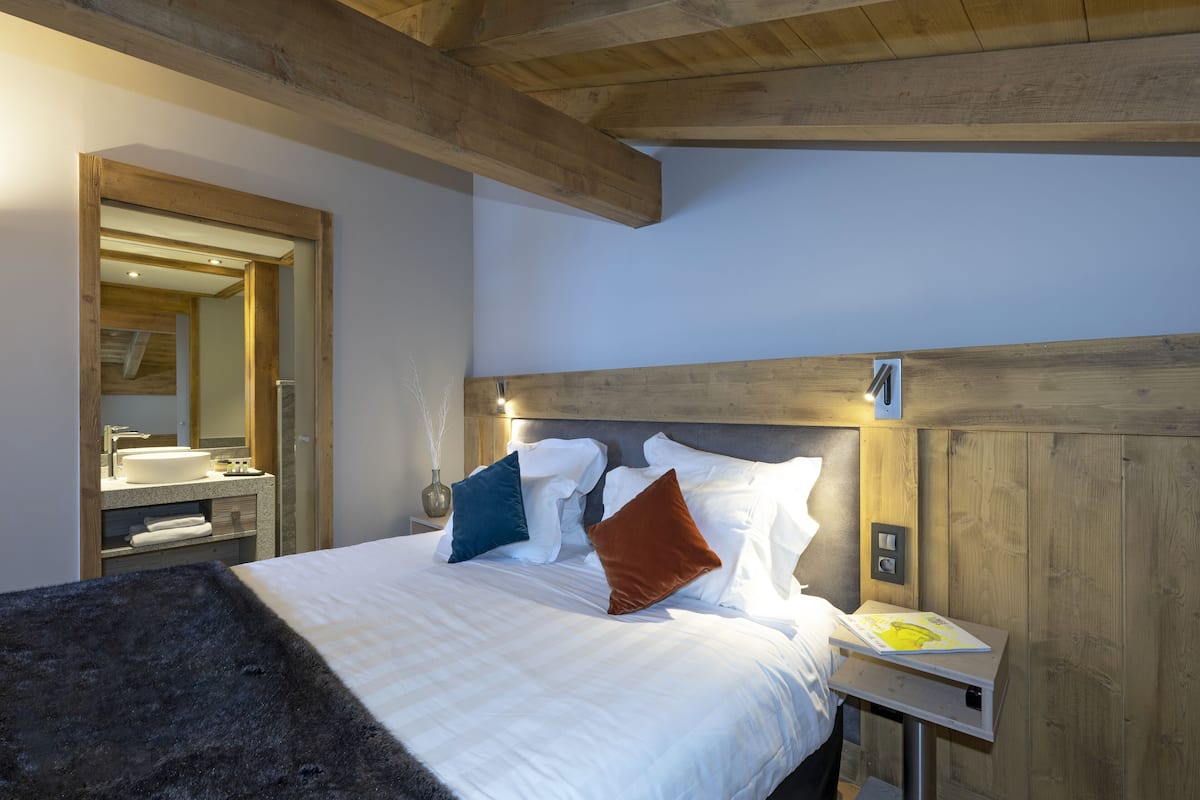 Un dormitorio con cabecera de madera, una mesita de noche con lámpara y un espejo.