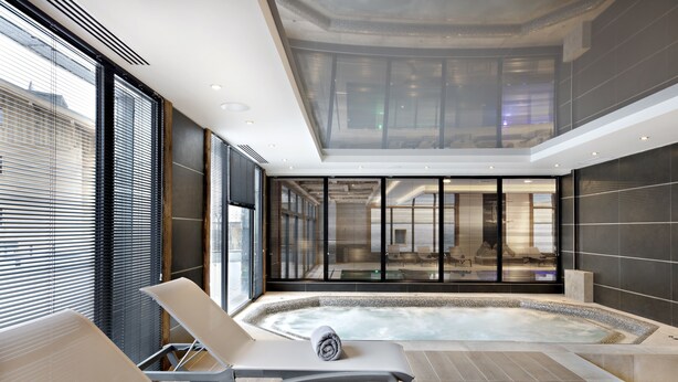 Un área de spa moderna con una bañera de hidromasaje, sillones reclinables y amplias ventanas.