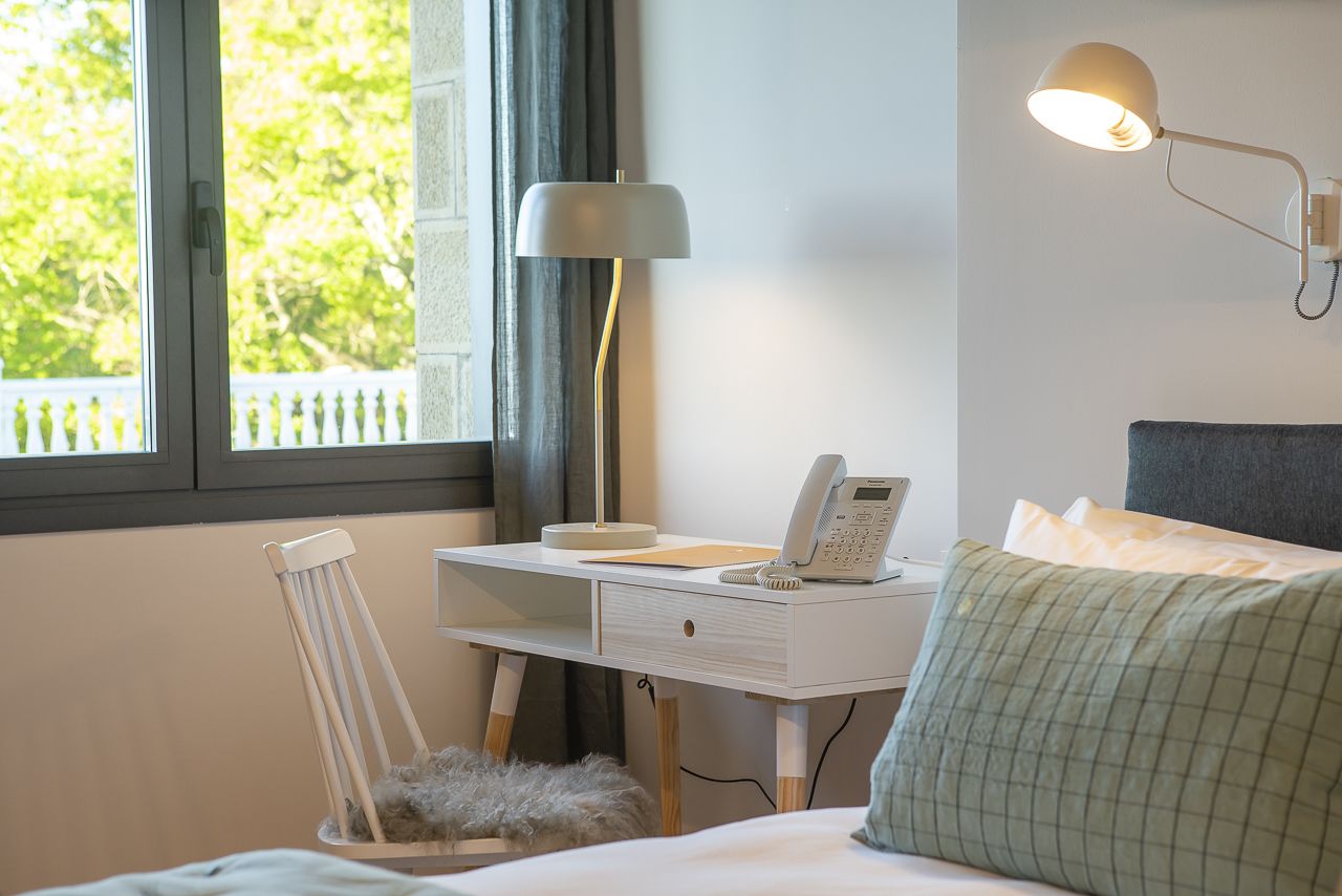 Une chambre à coucher avec un lit, un bureau avec un téléphone, une lampe et une chaise.