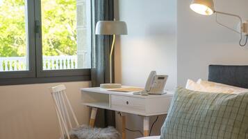 Une chambre à coucher avec un lit, un bureau avec un téléphone, une lampe et une chaise.