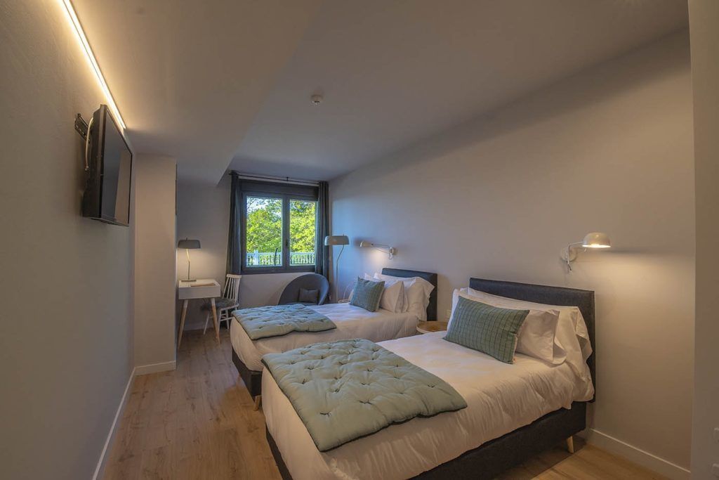 A bedroom with two beds, a desk, and a chair.