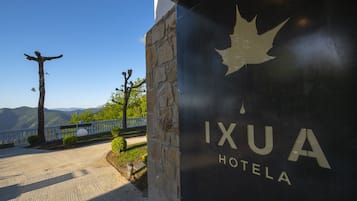 A hotel entrance with a stone facade and a view of mountains in the background.