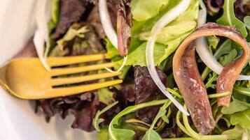 Une vue rapprochée d’une salade composée de différentes feuilles vertes et d’une saucisse.