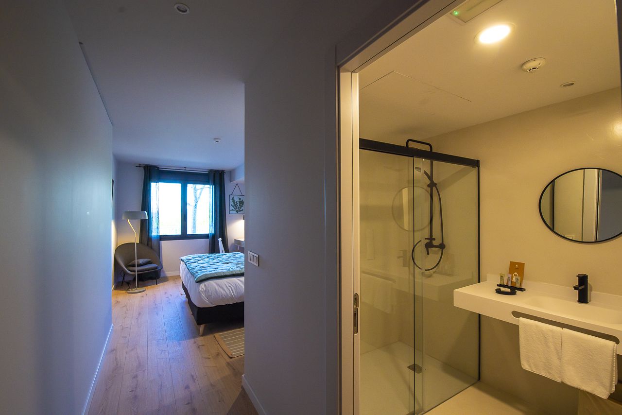 A modern bedroom with a bed, bedside table, and a window.
