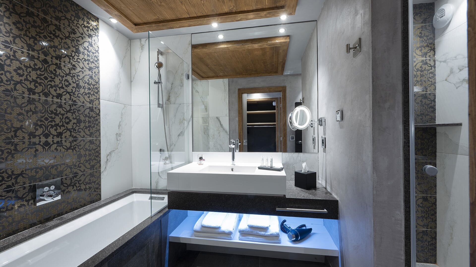 A modern bathroom with a glass-enclosed shower, a large mirror, and a vanity with a sink and towel rack.