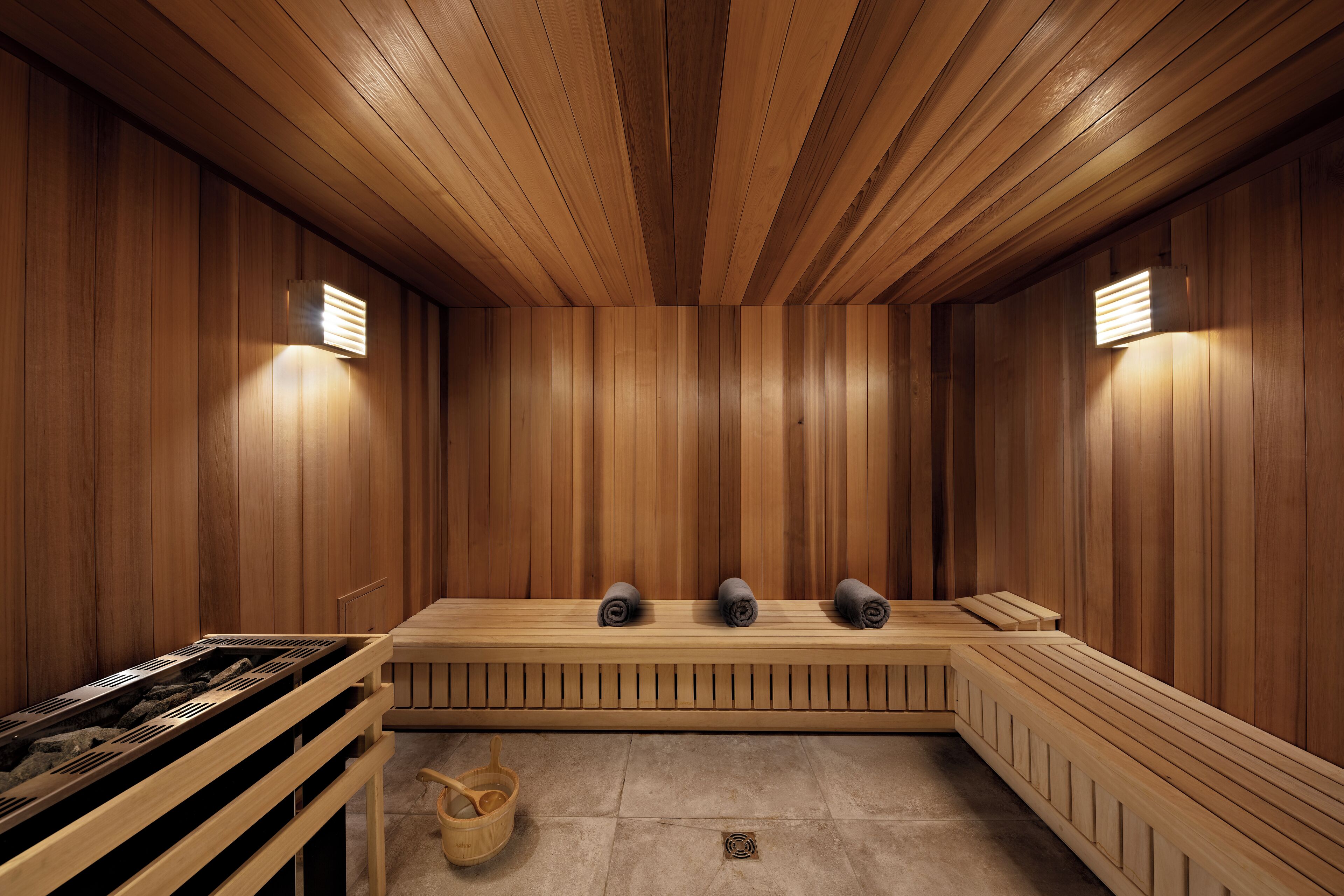 A sauna with wooden walls, benches, and a stone floor.