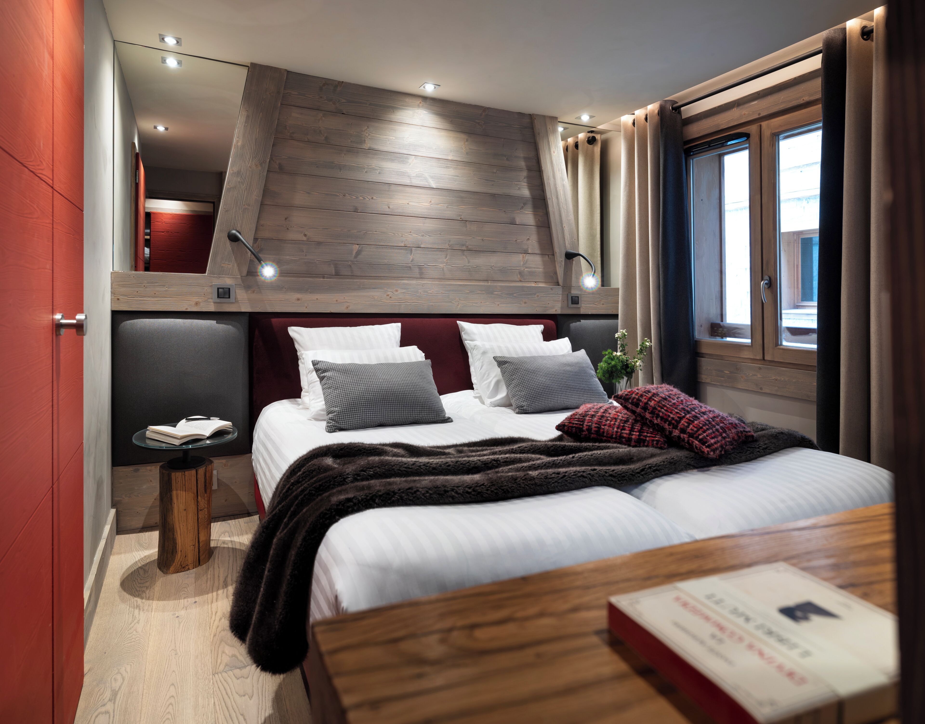 Un dormitorio con cama, mesita de noche y ventana con cortinas.