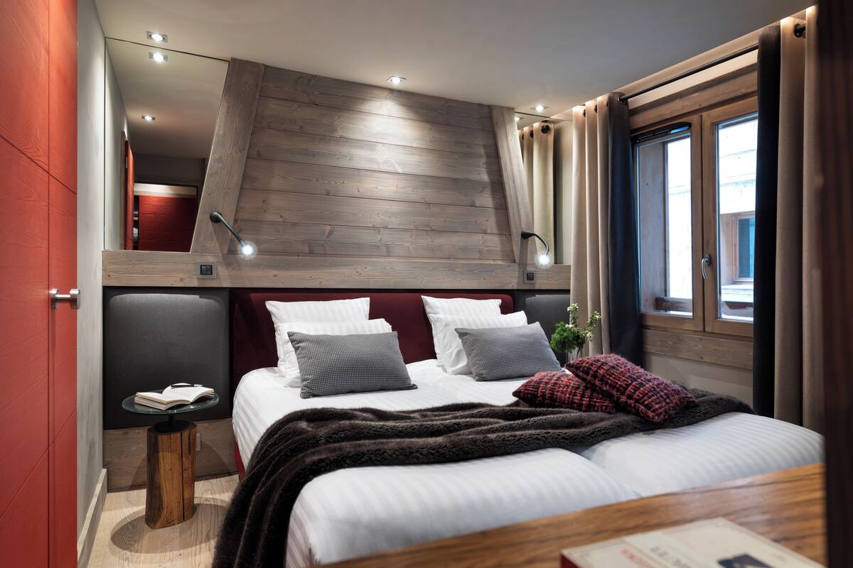 Un dormitorio con cama, mesita de noche y ventana con cortinas.