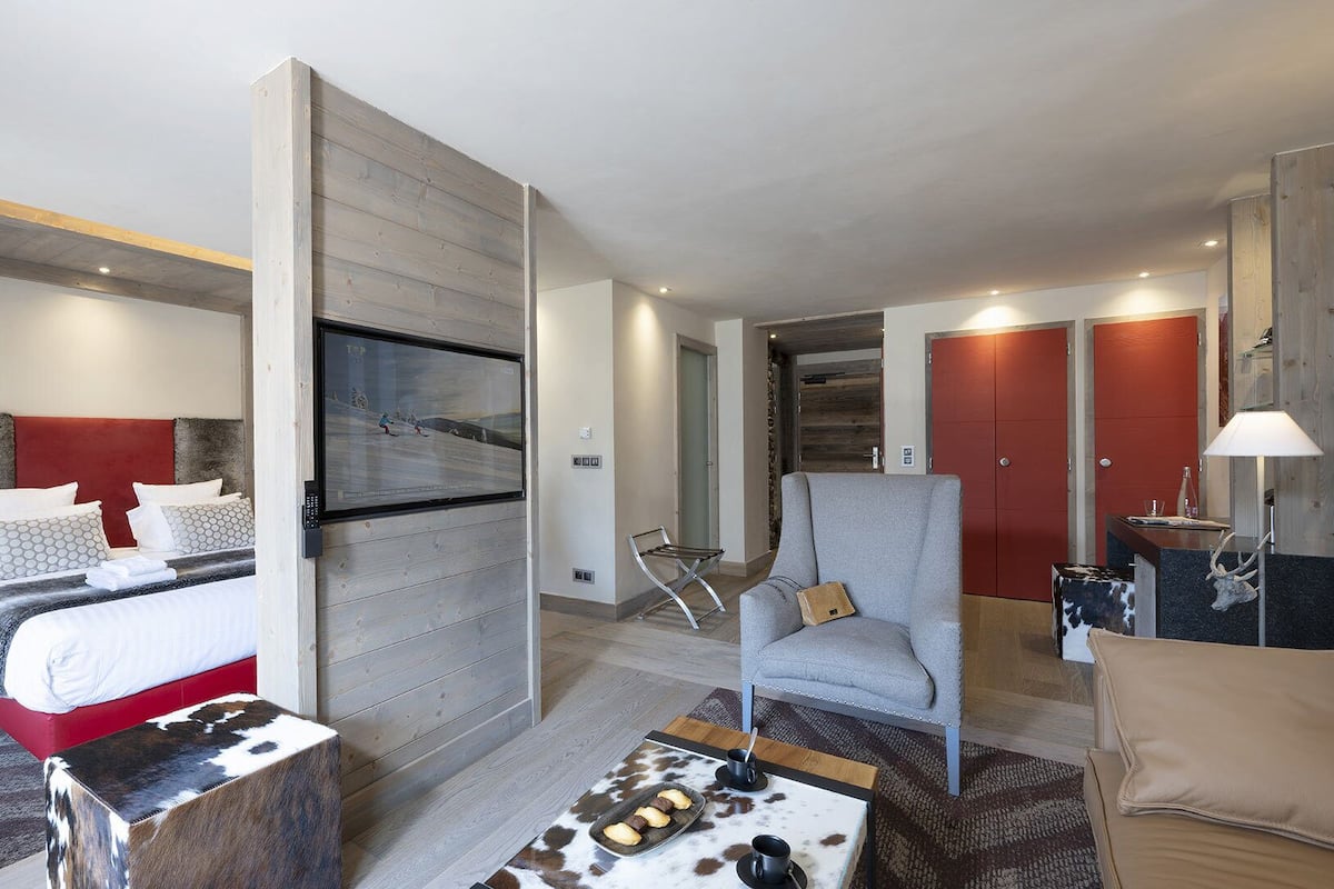 Una habitación de hotel moderna con cama, zona de estar, televisor y baño con ducha e inodoro.