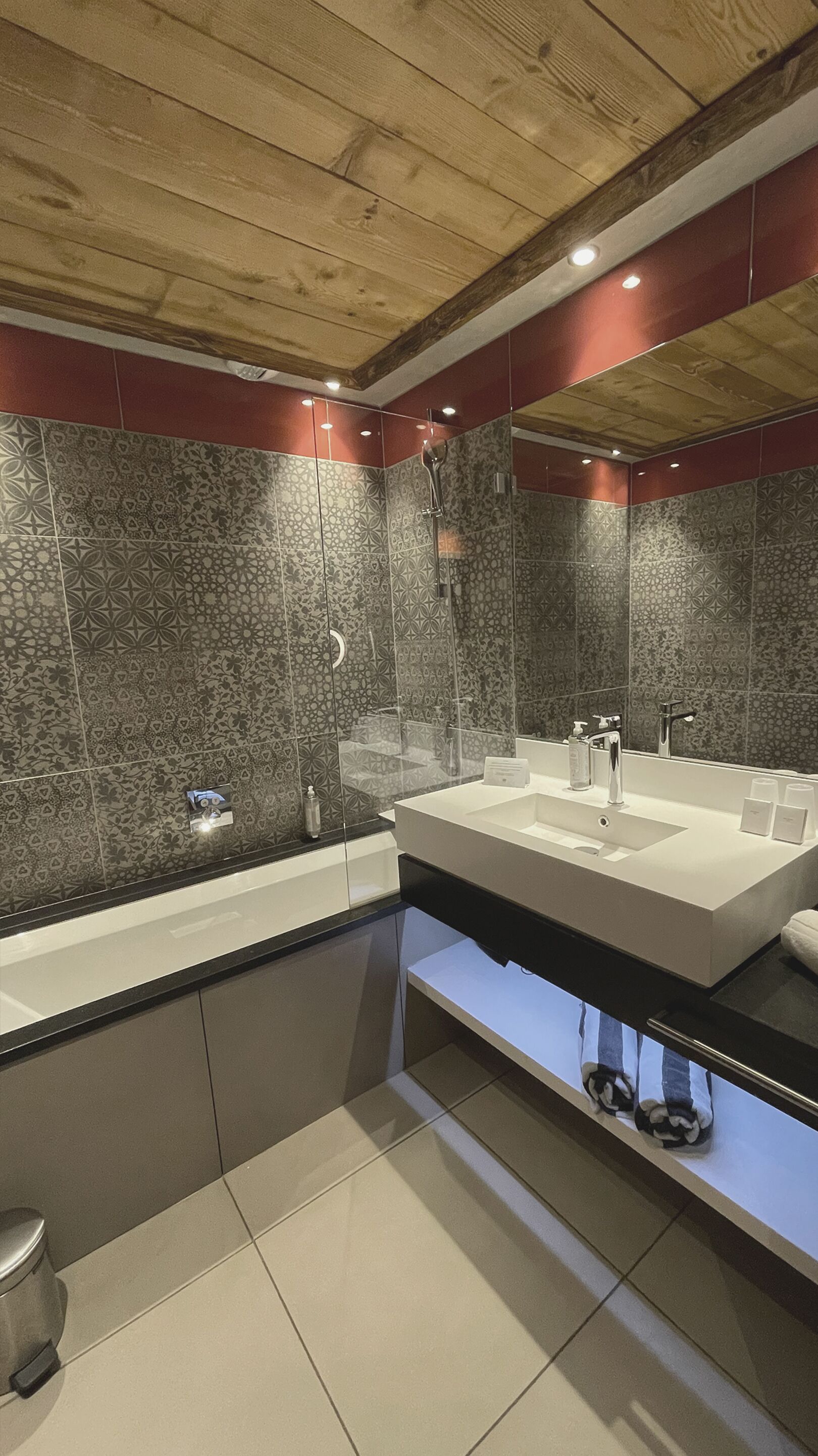 A modern bathroom with a large mirror, two sinks, and a shower.