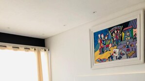 Une chambre d’hôtel avec un lit, une chaise, un tableau et une fenêtre avec des rideaux.