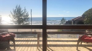 Une terrasse en bois offrant une vue sur l’océan et un bâtiment doté d’un toit recouvert de tuiles.