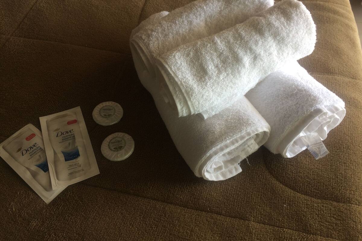 A bed with two neatly folded white towels and two Dove nutritional bars on a brown textured bedspread.