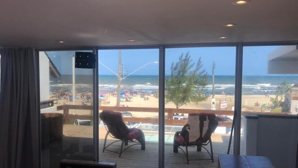 Un balcon donnant sur la plage, une table en bois et deux chaises.