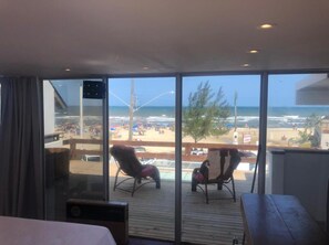 A balcony with a view of the beach, a wooden table, and two chairs. - Pousada Lili (Torres)