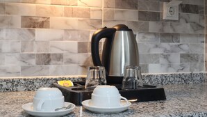 A kitchen with a marble backsplash, a coffee maker, two cups on a tray, and a box of tea bags. - Bolu Cadde Otel (Bolu)