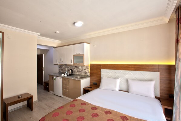 A hotel room with a bed, bedside tables, a small desk, a kitchenette, and a bathroom. - Bolu Cadde Otel (Bolu)