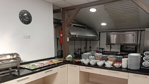 A modern kitchen with a buffet setup, stainless steel appliances, and a clock on the wall. - Bolu Cadde Otel (Bolu)