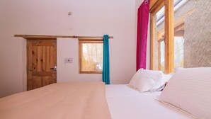 A bedroom with a wooden door, a window with a curtain, and a bed with white bedding. - Shangrila Resort Nubra (Leh)