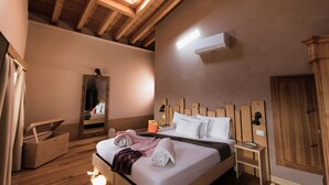 A bedroom with a wooden ceiling, a skylight, a bed with white linens, a wooden nightstand, and a mirror. - Agriturismo Milord (Salò)
