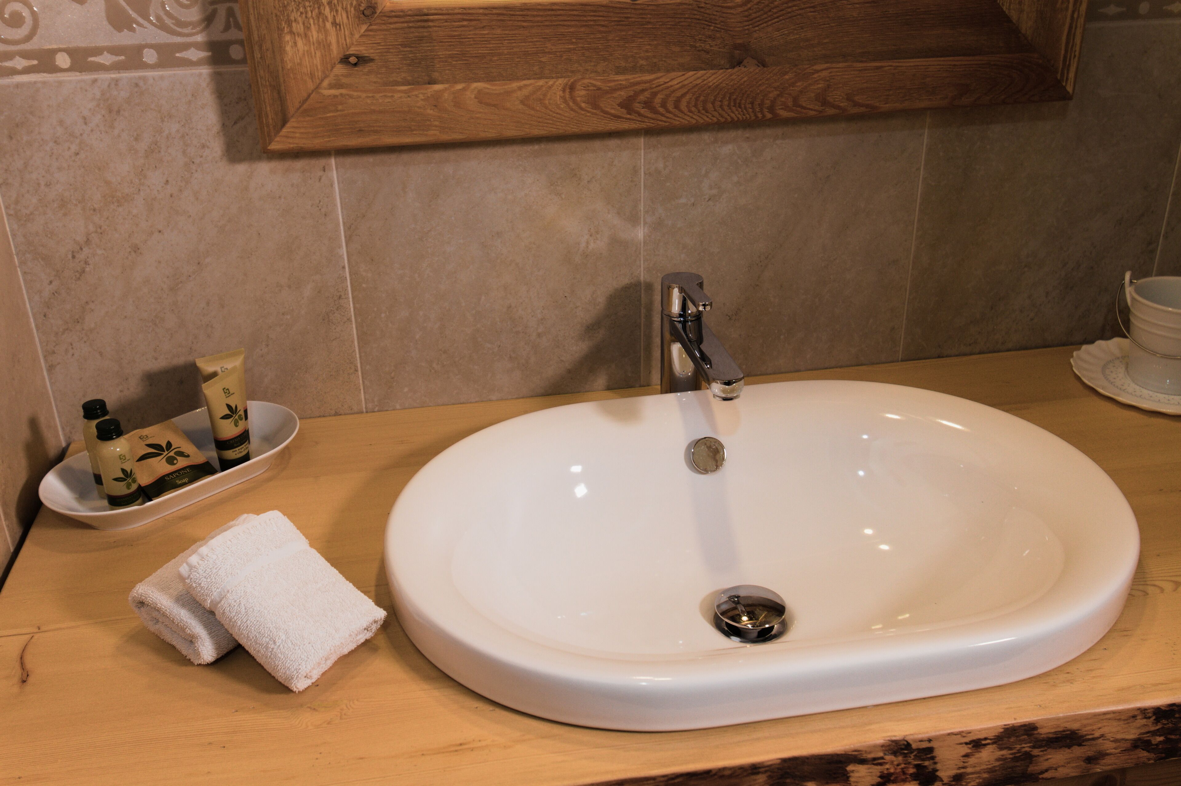 A bathroom with a white sink, a wooden countertop, a towel, and toiletries.