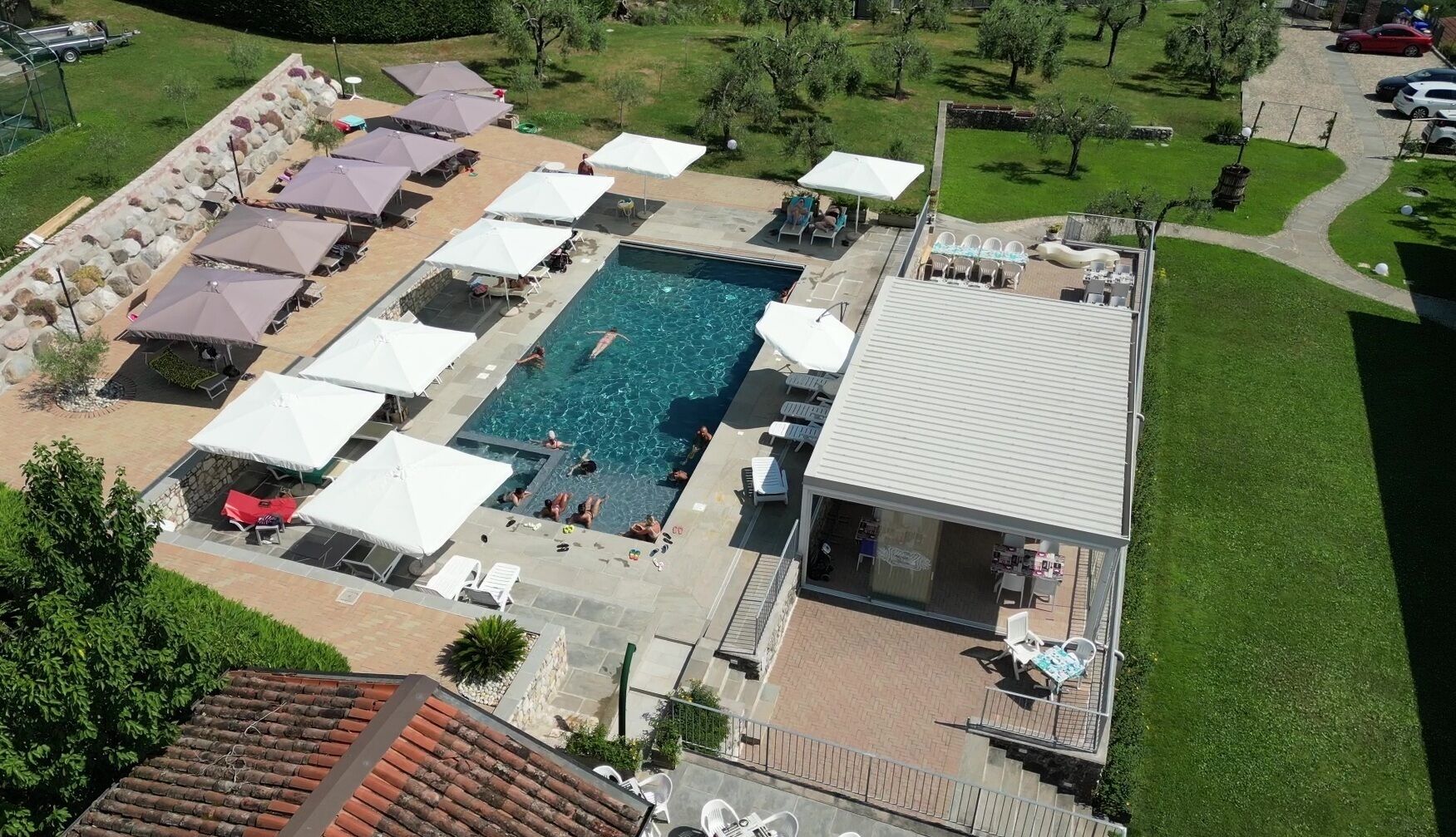 Vue aérienne d’un complexe hôtelier doté d’une piscine, de chaises longues et d’un patio couvert.