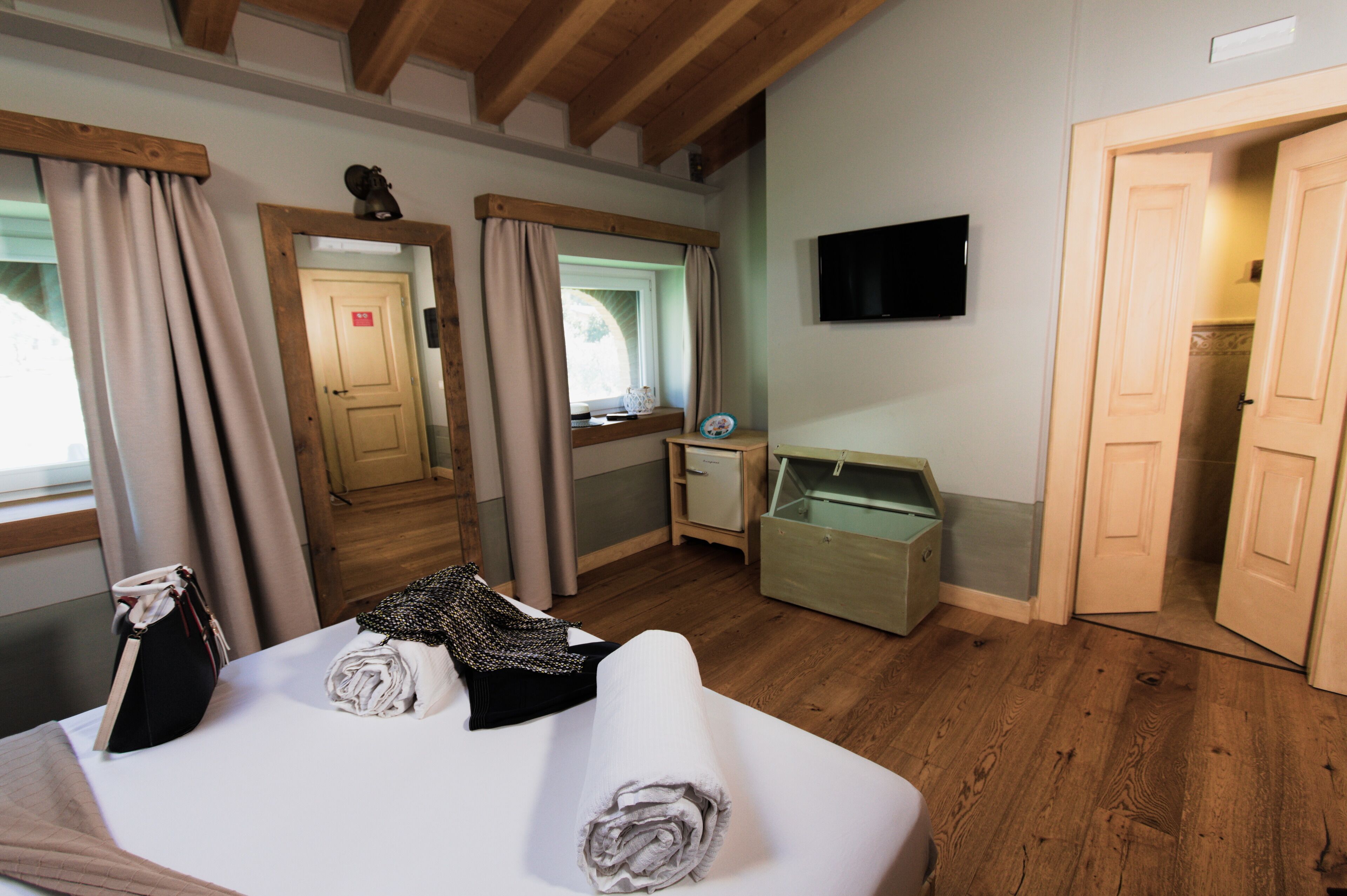 A hotel room with a bed, a desk, a television, and a bathroom door.