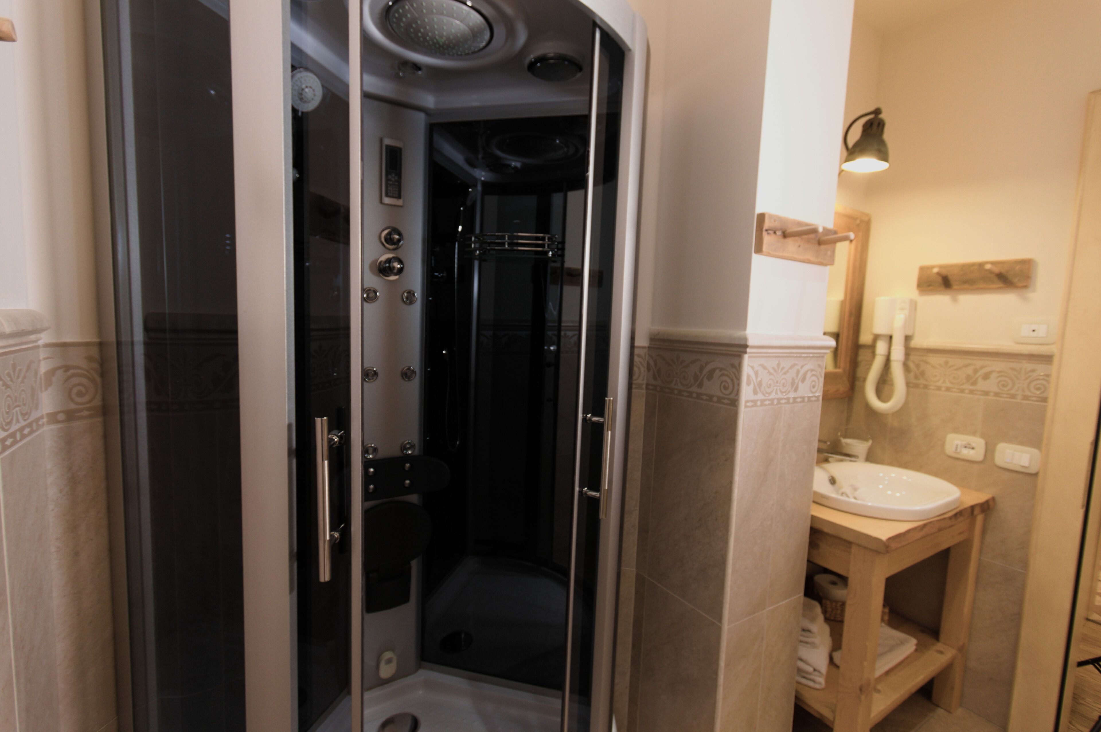 A modern bathroom with a glass-enclosed shower, a wooden vanity, and a wall-mounted toilet.
