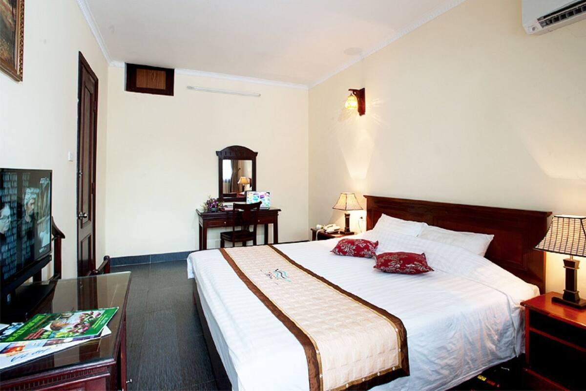Une chambre d’hôtel avec un lit, un bureau, une télévision et une lampe.