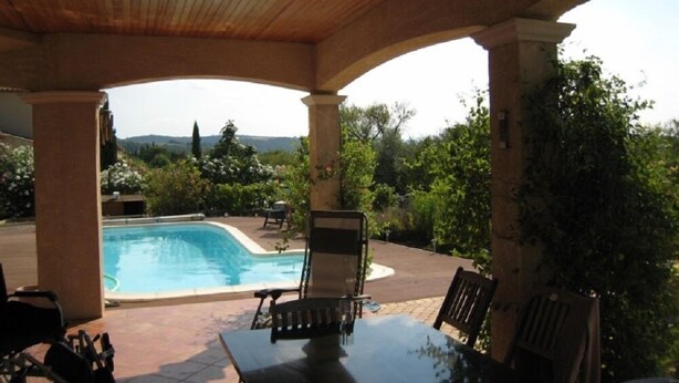 Un espace extérieur abrité comprenant une piscine, une table et des chaises.