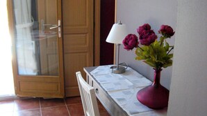 Un coin repas comprenant une table, des chaises, un vase avec des fleurs, une lampe et une porte-fenêtre coulissante.