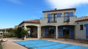 Une maison à deux étages avec une piscine recouverte de bâches bleues.