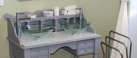 A bathroom with a double sink, a mirror, and a towel rack.